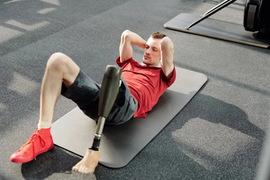 Man performing sit-ups on yoga mat using prosthetic leg in fitness gym.