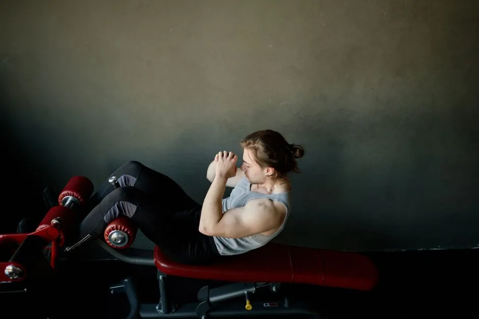 Focused young man doing abdominal exercises on a gym bench.