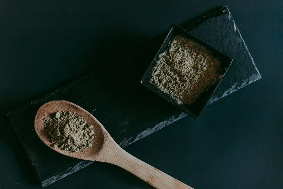 Overhead shot of brown sugar in a wooden spoon and black ceramic bowl on dark slate.