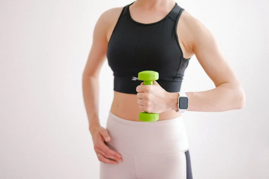 A woman in activewear using a dumbbell and smartwatch during a home workout.