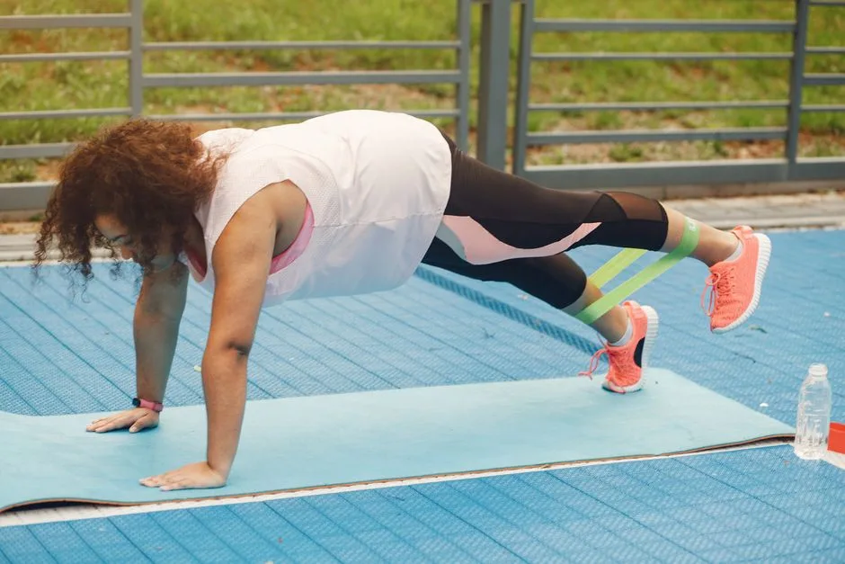 Woman working out on a yoga mat outdoors using a resistance band for a healthy lifestyle.