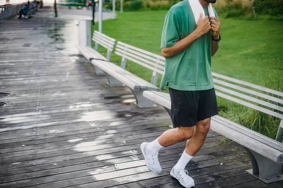 A man in a green shirt goes for a jog on a wooden boardwalk, promoting a healthy lifestyle.