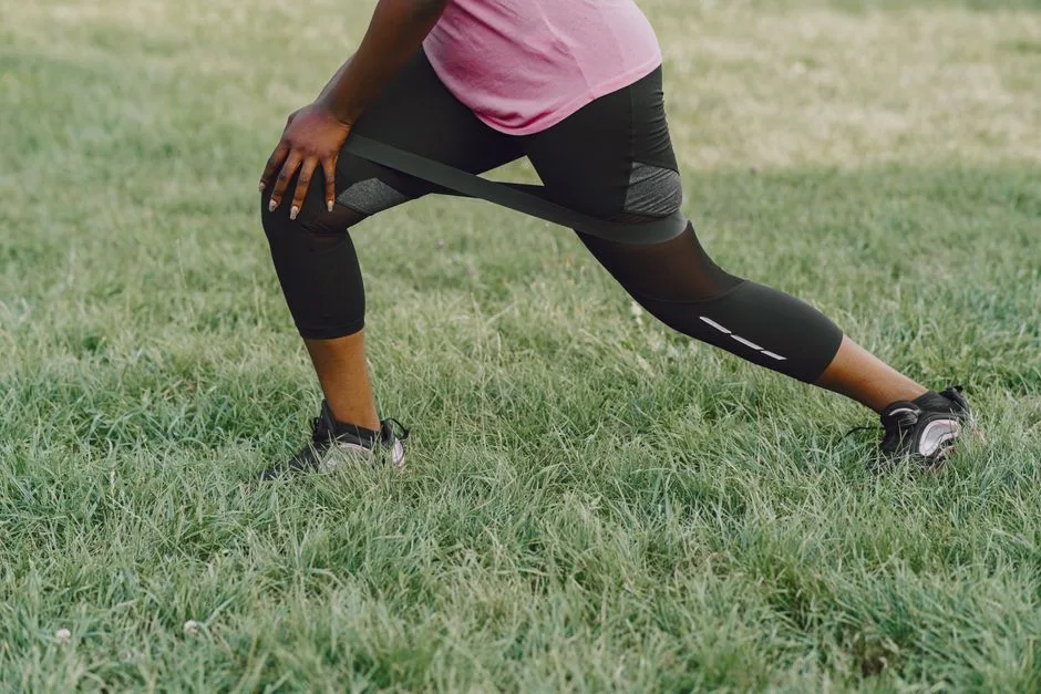 A woman performs resistance exercises outdoors, focusing on leg strength.