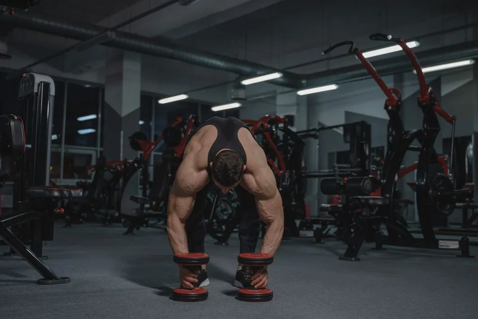 Muscular man in a gym lifting heavy dumbbells showcasing strength and fitness.