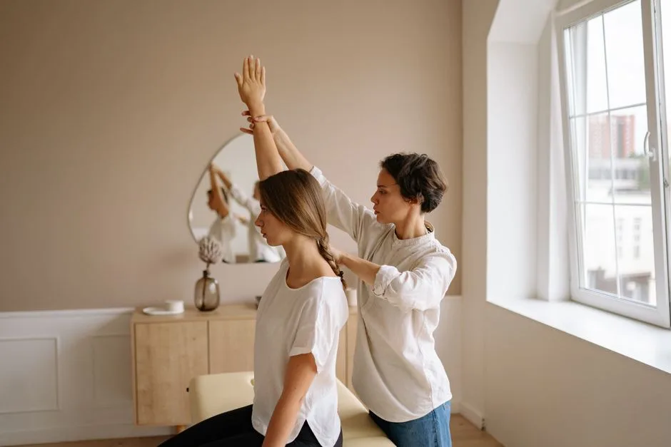 A therapist guides a woman through a stretching exercise in a calm, indoor setting.
