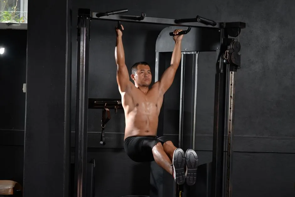 A shirtless man doing a workout with pull-up bar indoors at a gym, showcasing fitness and strength.