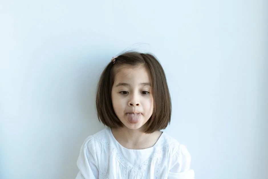 Cute young girl playfully sticking out her tongue, showcasing innocence and fun.