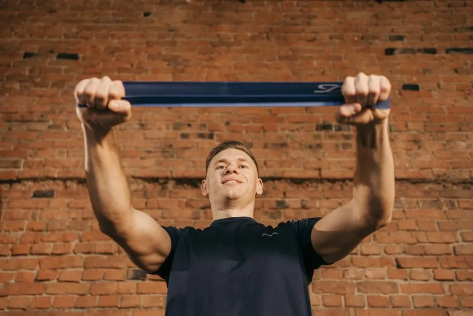 Man performing workout with resistance band against a brick wall backdrop.