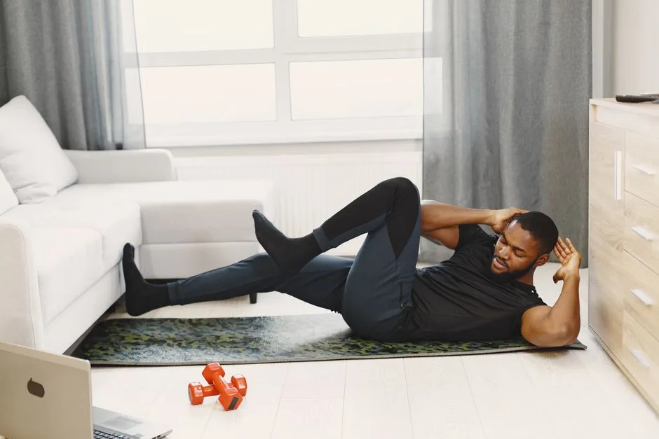 A black man performing abdominal exercises on a yoga mat at home.