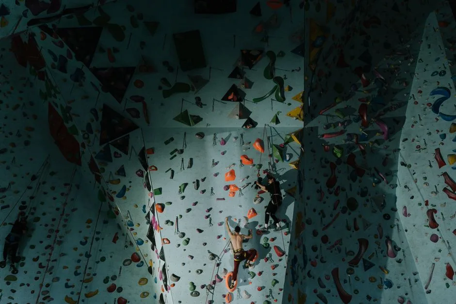 Dynamic scene of athletes engaged in indoor rock climbing on a colorful wall.