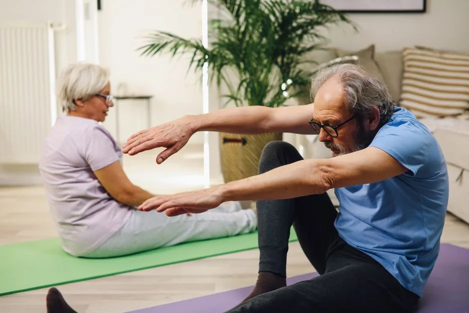 Elderly couple practicing yoga indoors with focus on wellness and fitness.