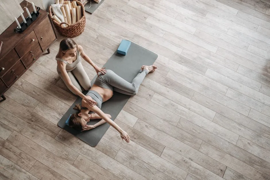 Expectant mother with trainer practicing pregnancy yoga indoors on a mat.