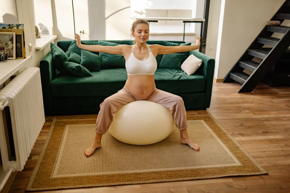A pregnant woman practices stretching exercises on a yoga ball in a cozy living room setting.