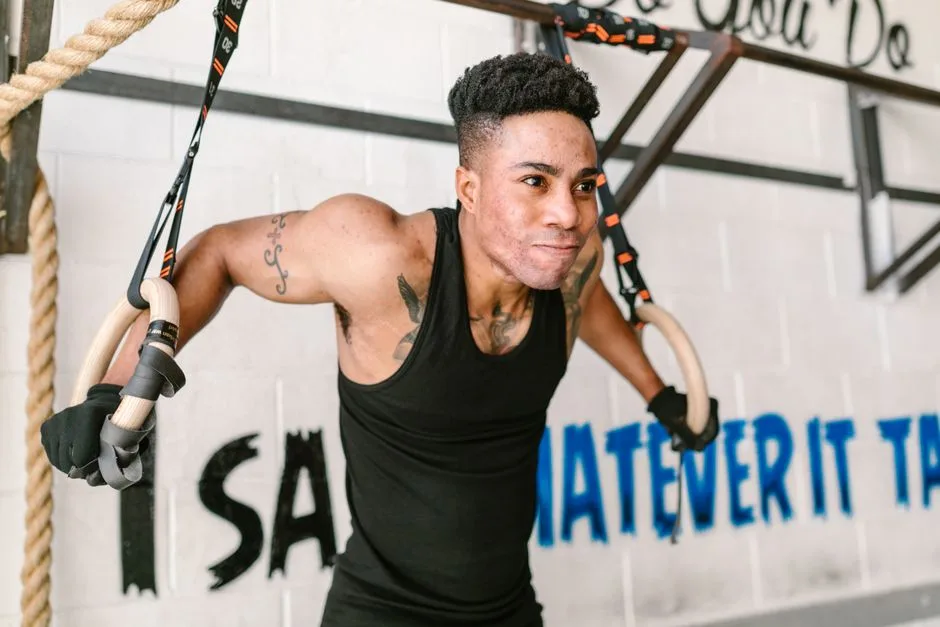 A determined athlete performs exercises on gymnastic rings in a gym setting.