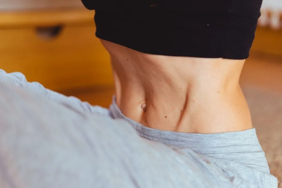 Close-up of a fit person's torso wearing sportswear, emphasizing toned muscles.