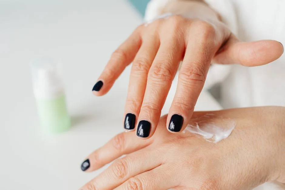 Close-up of a woman applying hand cream for moisturizing.