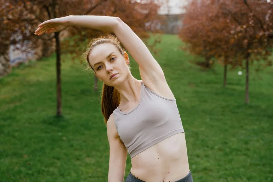 An athletic woman stretches in a green park; promoting outdoor fitness and wellness.