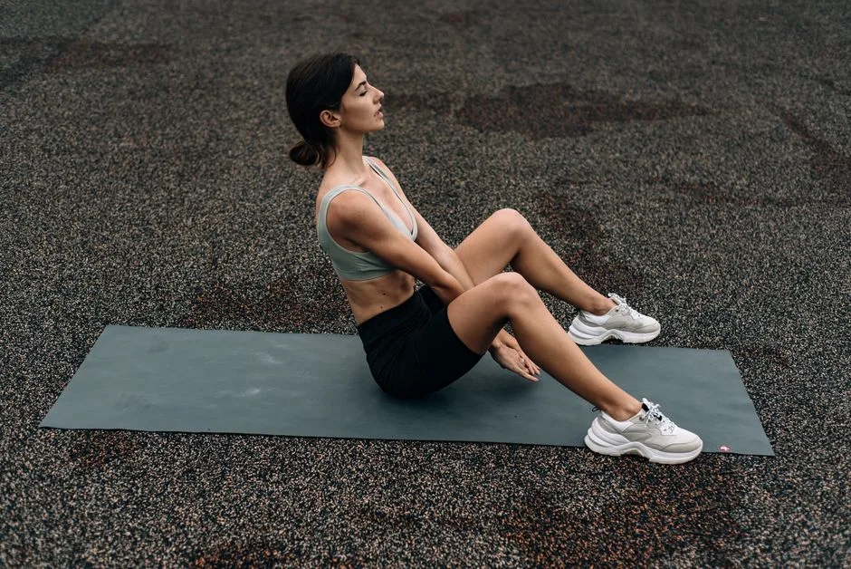 Woman sitting on yoga mat outdoors in an urban setting, embodying fitness and relaxation.