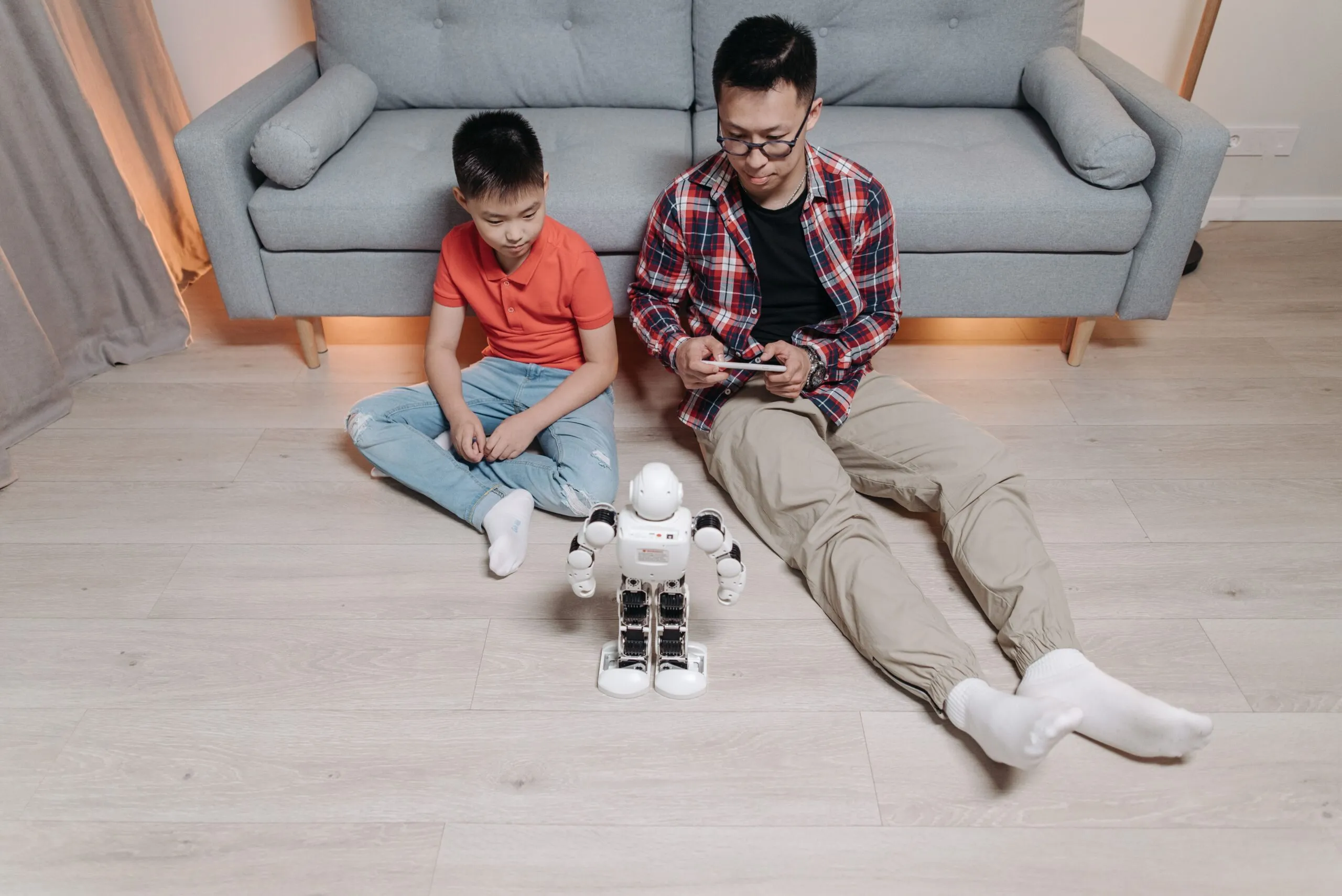 Father and son bonding over robotics and technology at home, enjoying playful interaction with a robot.
