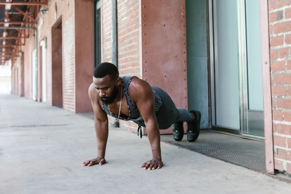 A man performs push-ups outside against a brick wall, showcasing strength and fitness.