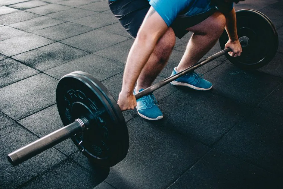 A man deadlifting a barbell indoors showcasing power, fitness, and dedication.