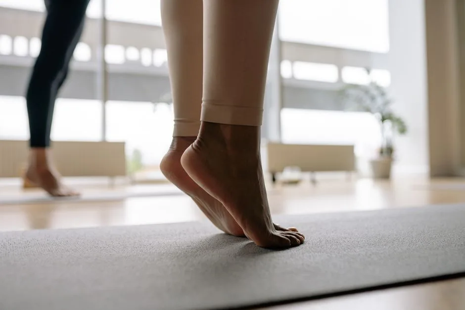 Detail shot of bare feet balancing on a yoga mat inside a bright studio.