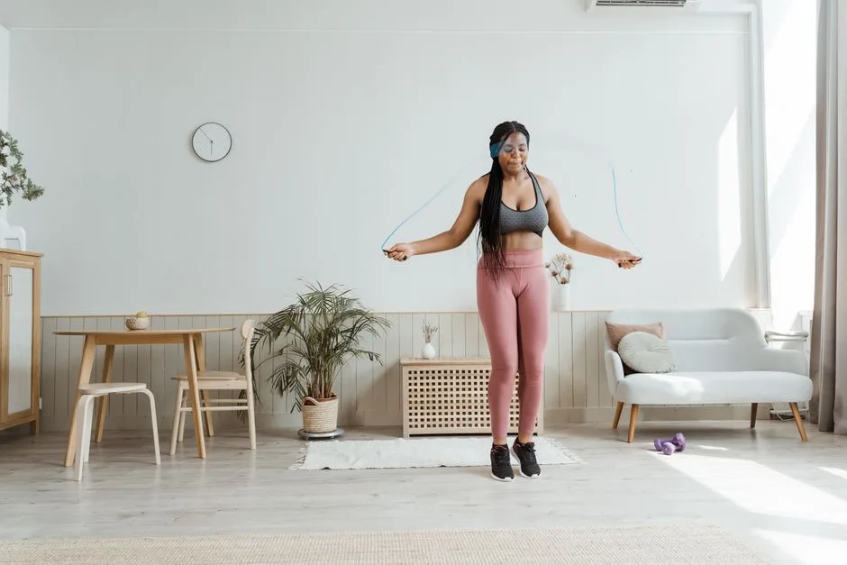 Confident black woman in activewear jump roping at home, promoting wellness and body positivity.
