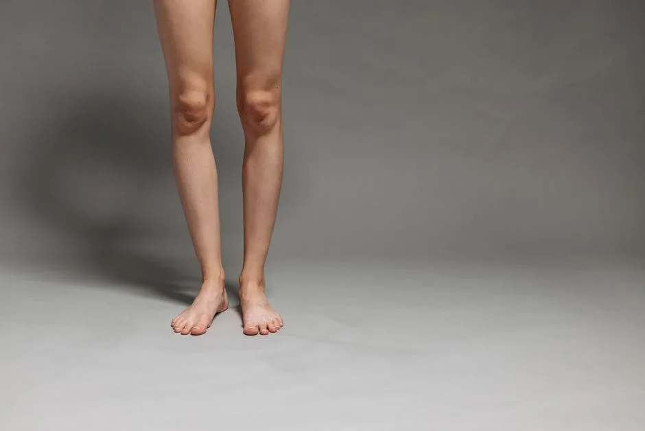 Studio shot of a person's lower legs and feet on a gray background.