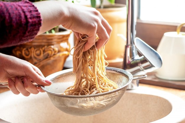 A woman is cooking soba noodles in her kitchen.