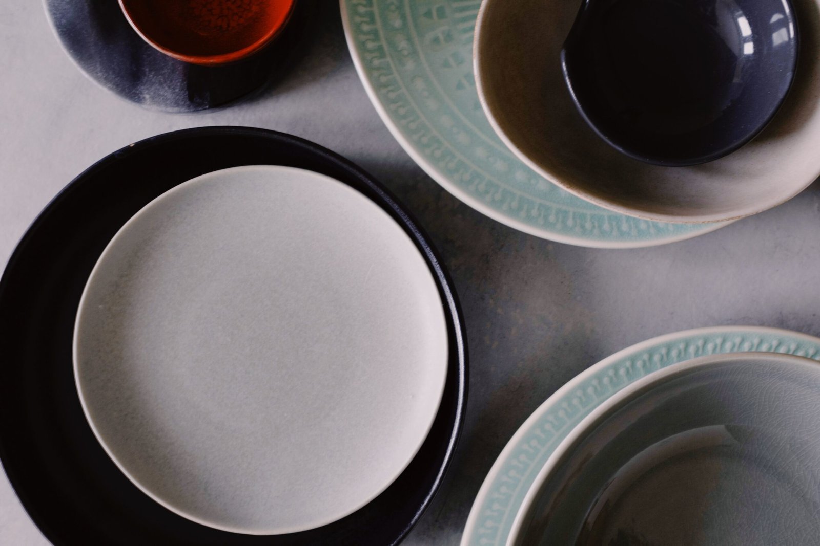 A collection of elegant ceramic plates and bowls showcasing a minimalist design in neutral tones.