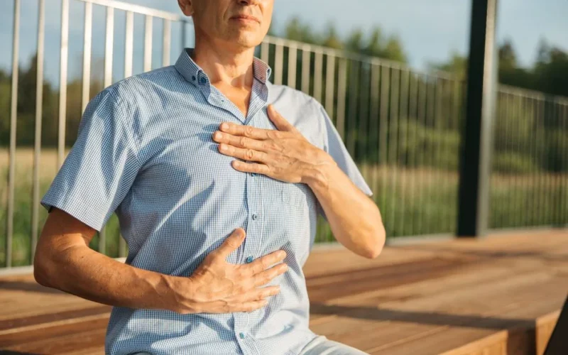 A man practicing relaxation with hands on chest and abdomen outdoors.