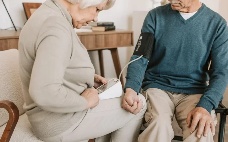 Senior couple at home measuring blood pressure for health check.
