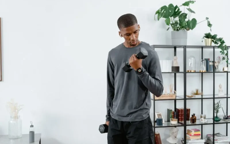 Young man exercising with dumbbells indoors for a healthy lifestyle.