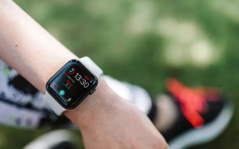 Close-up of a smartwatch on a wrist showing health metrics outdoors on a sunny day.