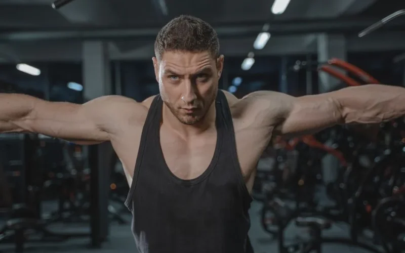 Focused man in activewear exercising in a gym environment.