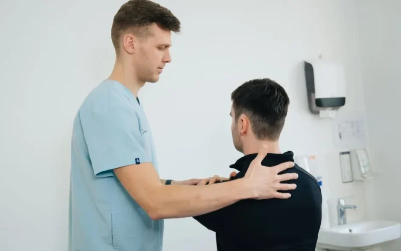 Physiotherapist working with a patient in a clinical setting, focusing on shoulder therapy.