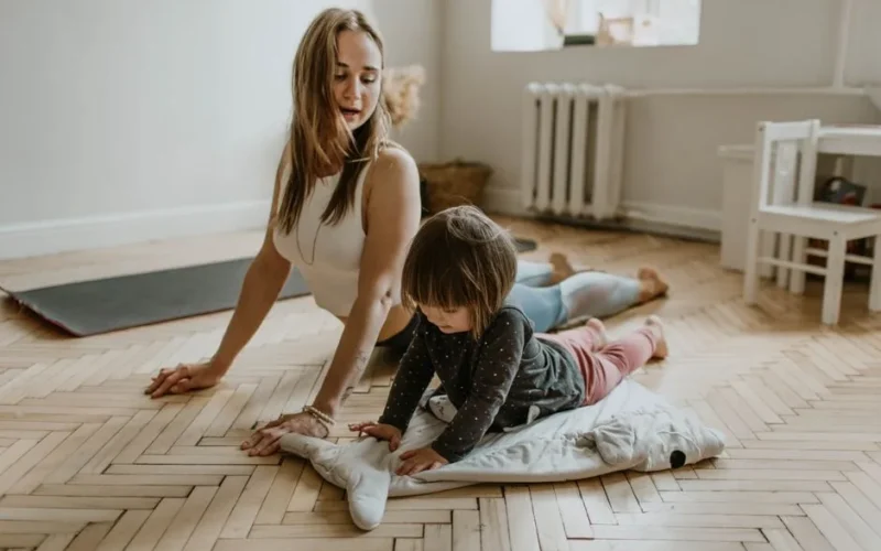 A mother and child practicing yoga together at home on a sunny day, fostering wellness and connection.