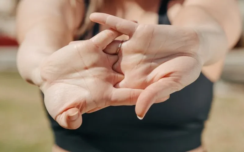 A woman's hands stretching outdoors, highlighting relaxation and fitness concepts.