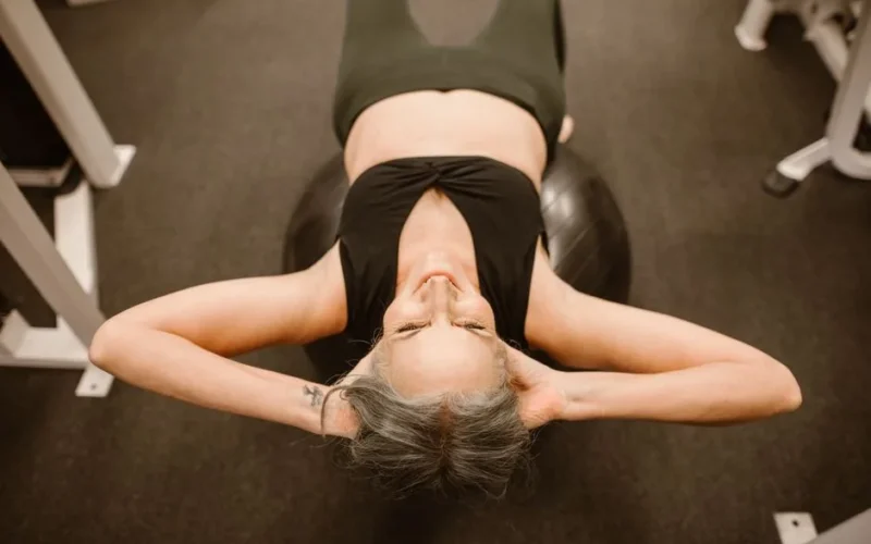 Senior woman performing exercise on stability ball for fitness and strength.