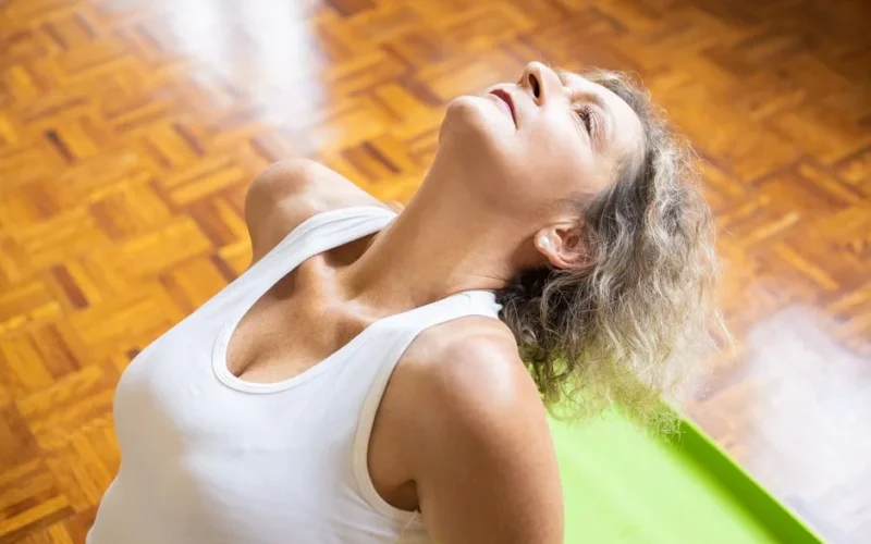 An elderly woman stretching on a yoga mat, promoting fitness and a healthy lifestyle.