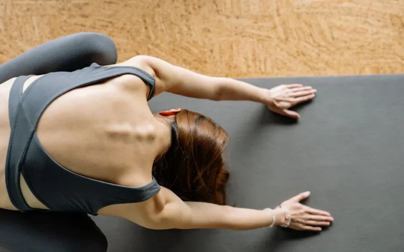 Top view of a woman in yoga pose on a mat with focus on posture and relaxation.