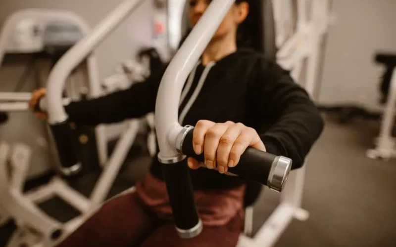 Close-up of a woman using a chest press machine in the gym for strength training.