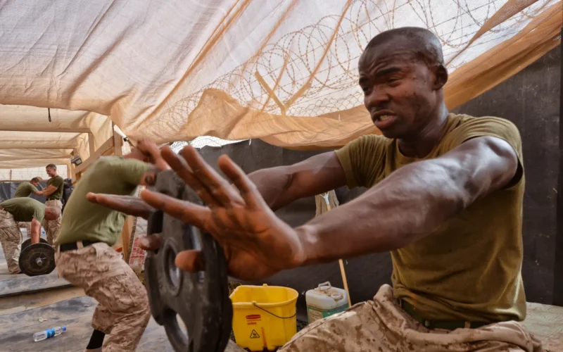 Cpl. Lud G. Romain, assistant supply warehouse chief, Headquarters and Service Company, Combat Logistics Battalion 4, 1st Marine Logistics Group (Forward), holds a weight at arm’s length during a workout here, July 14. The combat conditioning session marked the end of the seven-week course.