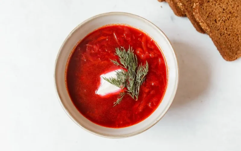 Delicious overhead view of traditional borsch soup with garnish and rye bread slices.