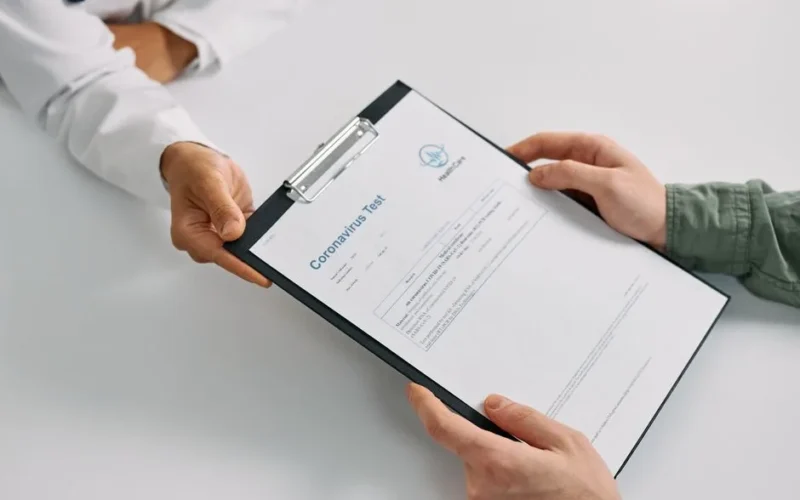 A doctor hands over coronavirus test results to a patient during a consultation in a medical clinic.