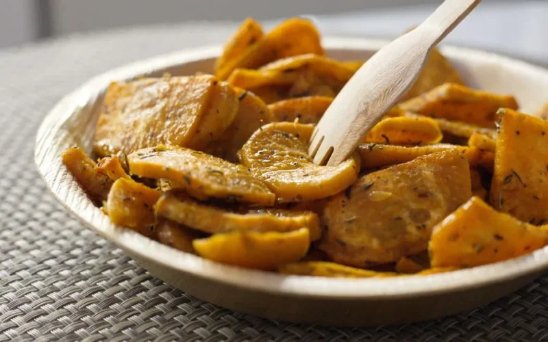 Closeup of bowl full of crispy baked sweet potatoes with herbs and eco friendly bamboo fork