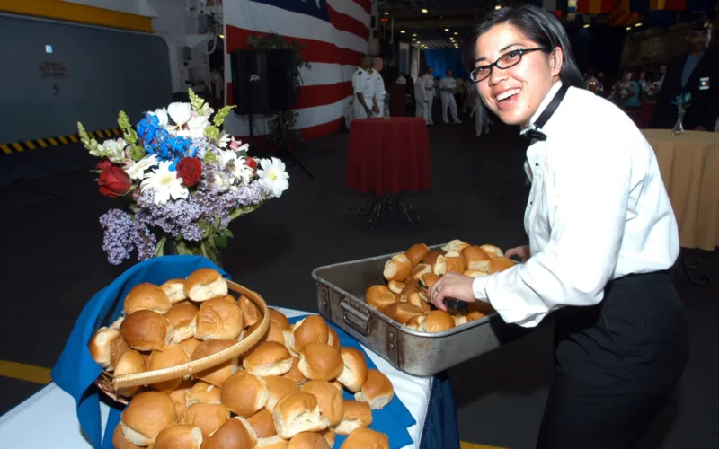 New York (May 28, 2006) - Culinary Specialist 3rd Class Siriphone Phakdy places fresh rolls on one of the reception tables set up in the hangar bay of the amphibious assault ship, USS Kearsarge (LHD 3). Kearsarge hosted a sunset reception as a show of appreciation for New York during Fleet Week 2006. Fleet Week has been sponsored by New York City since 1984. The annual event also provides an opportunity for citizens of New York City and the surrounding Tri-State area to meet Sailors and Marines as well as witness first hand the latest capabilities of today's Navy and Marine Corps team. Fleet Week includes dozens of military demonstrations and displays, including public tours of many of the participating ships. U.S. Navy photo by Mass Communication Specialist 2nd Class Valerie S. Guffey (RELEASED)