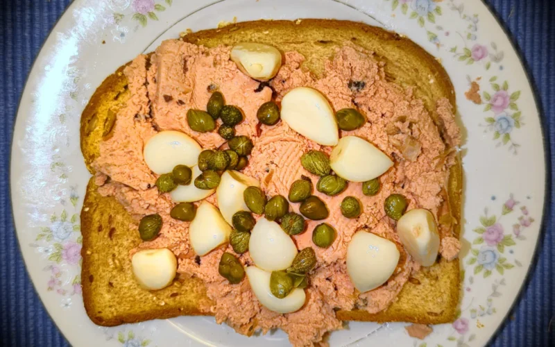 Pork liver pate with mushrooms, pickled garlic, and capers, on whole grain bread - Massachusetts, USA.
