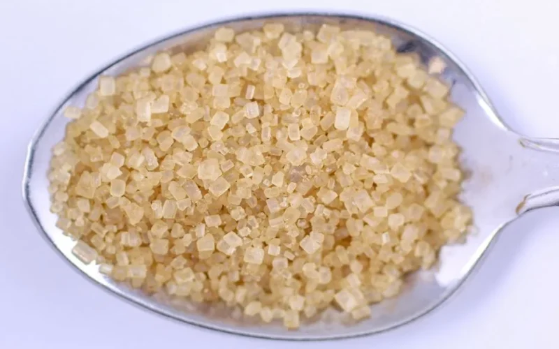 Detailed close-up of raw brown sugar on a metal spoon, perfect for food and cooking themes.