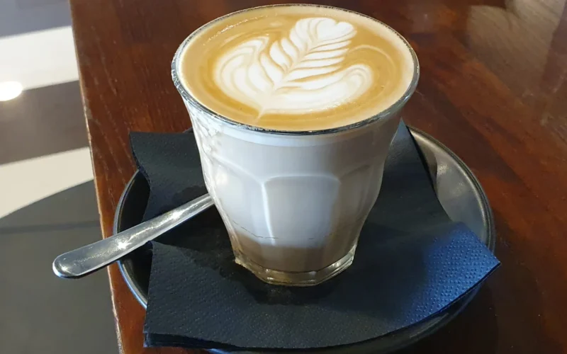 A typical caffe latte (or just "latte") served in a good café in Woodville, South Australia. As traditional, it is served in a glass, and the microfoam is free poured onto the coffee (espresso) to form a pattern (latte art).